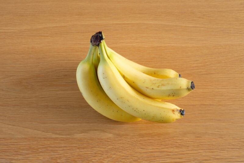 on a wooden surface is a bunch of ripe yellow bananas