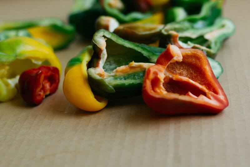 closeup image of sliced green, yellow, and red bell peppers