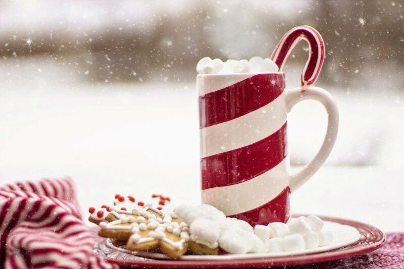 best-alcohol-for-christmas-punch- | Food For Net a candy cane patterned mug with marshmallows on top and snow falling around it to represent the best alcohol for Christmas punch