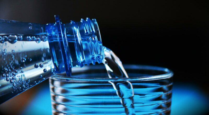 close up of water being poured from a bottle into a glass to represent the best bottled water brands