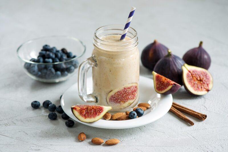 a smoothie in a jar surrounded by blueberries and figs to represent the best collagen protein powder