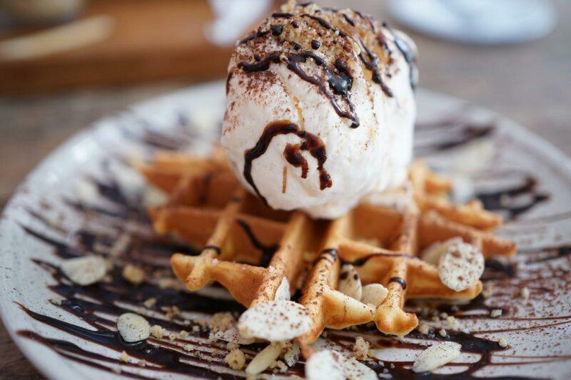 a waffle with a scoop of ice cream and chocolate drizzle on a plate to represent the best ice cream brands 