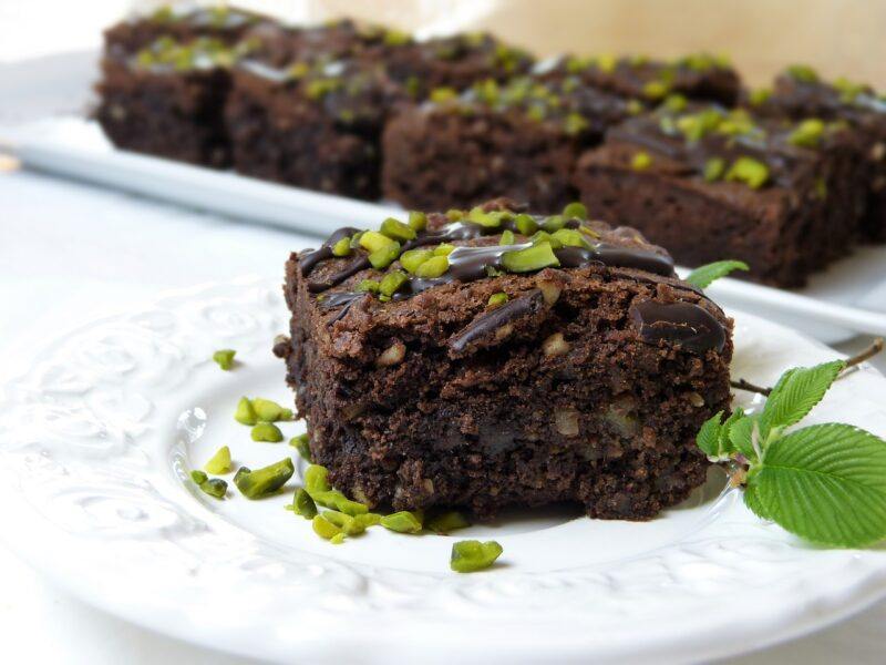 A close up of a brownie topped with nuts with more brownies in the background to represent the best plant-based dessert 