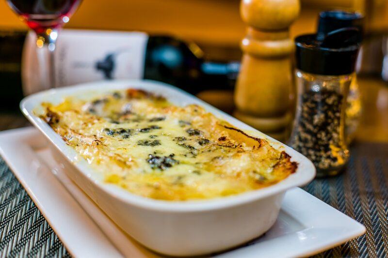 a small dish of lasagna with spice bottles in the background to represent the best plant-based lasagna