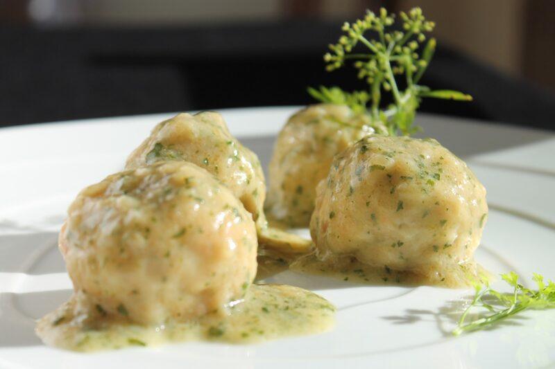 light colored meatballs with sauce and garnish on a white plate to represent the best plant based meatballs 