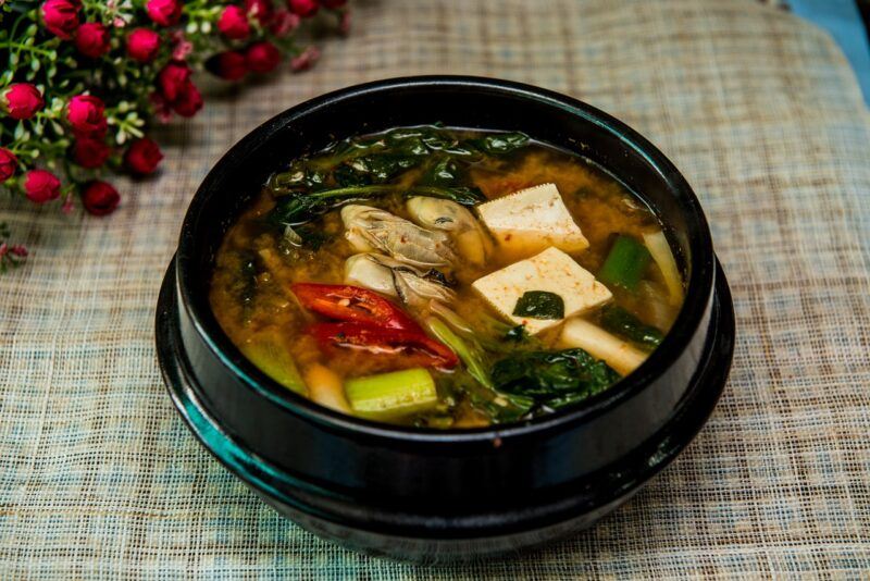 vegetable soup in a black bowl with roses in the background to represent the best plant-based soups 