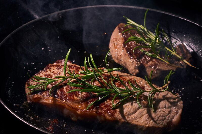 two steaks in a black pan with rosemary garnish to represent the best plant-based steaks