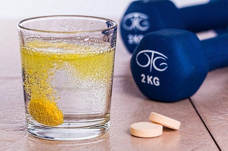 best-protein-powder-with-creatine | Food For Net a glass with tablets dissolving in it sitting next to a set of weights to represent the best protein powder with Creatine