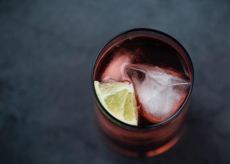 a top view of a full glass with a lime wedge and ice cube to represent the best spanish brandy