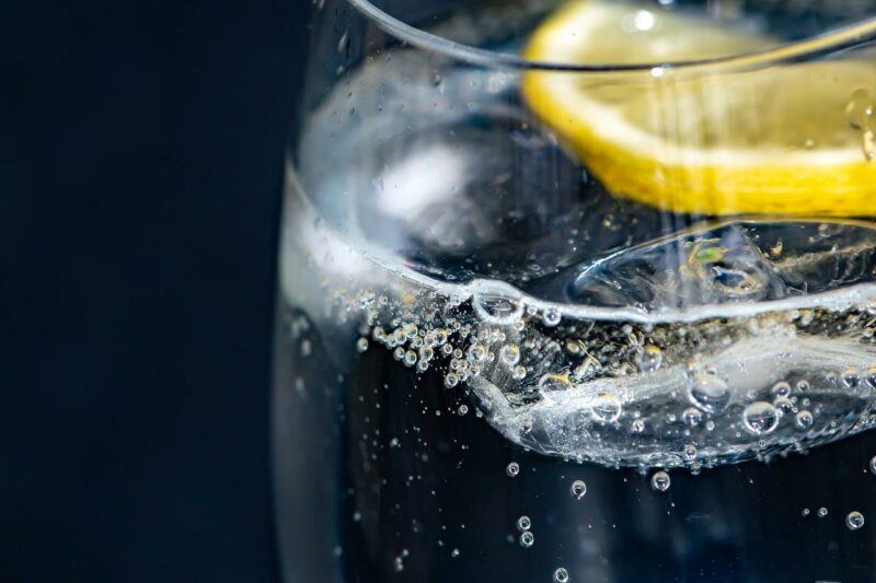 a close up of a glass of sparling water with lemon and a dark background to represent the best sparkling water brands