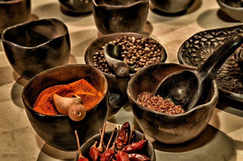 various spices in dark brown wooden bowls with wooden spoons and scoops to represent the best spice brands