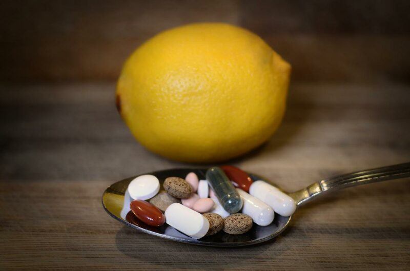 a lemon on a table with a spoonful of vitamins and supplements to represent the best supplement brands