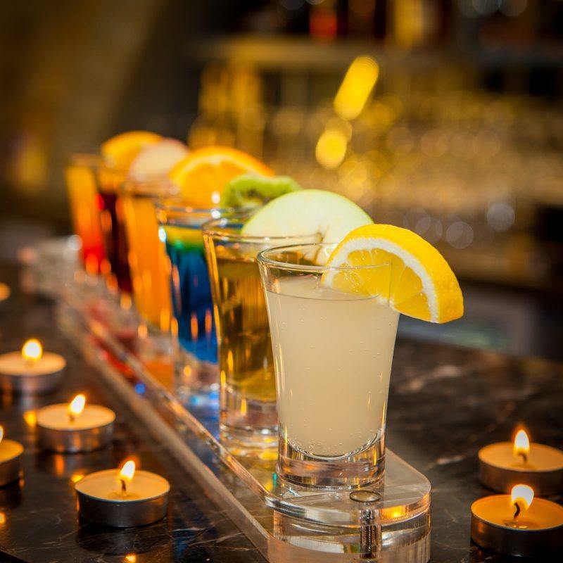 colorful shots lined up on a bar with tea light candles surrounding them to represent the best tequila for shots 