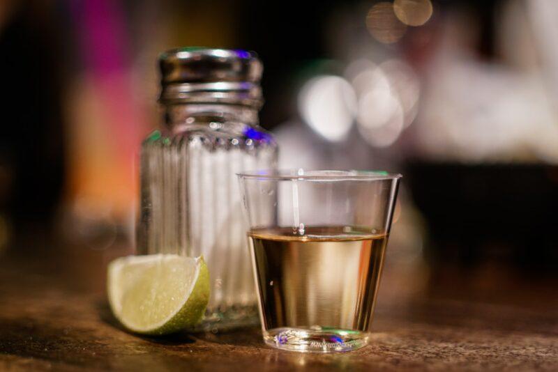 best-tequila-shots | Food For Net a close up of a gold tequila shot, lime wedge, and salt shaker to represent the best tequila shots