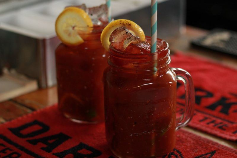 two bloody mary's in jars with lemon garnishes to represent the best vodka for a bloody mary