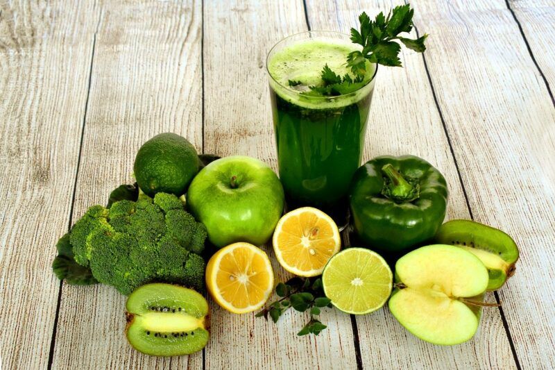 a bunch of green fruits and veggies surrounding a green smoothie to represent the best zero carb protein powder 