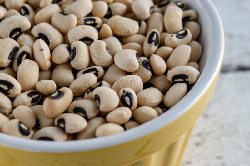 a closeup image of a yellow bowl with white rim full of black-eyed peas or cowpeas