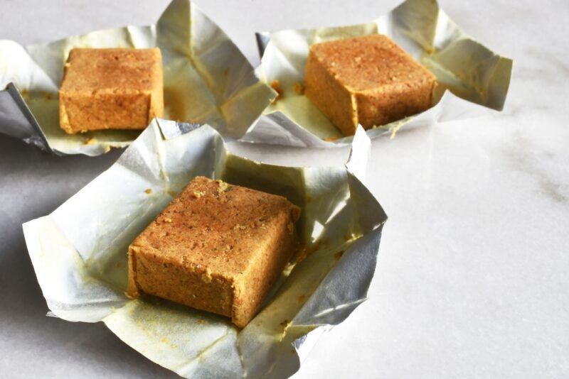 on a marbled surface are three bouillon cubes resting on their foil wrappers