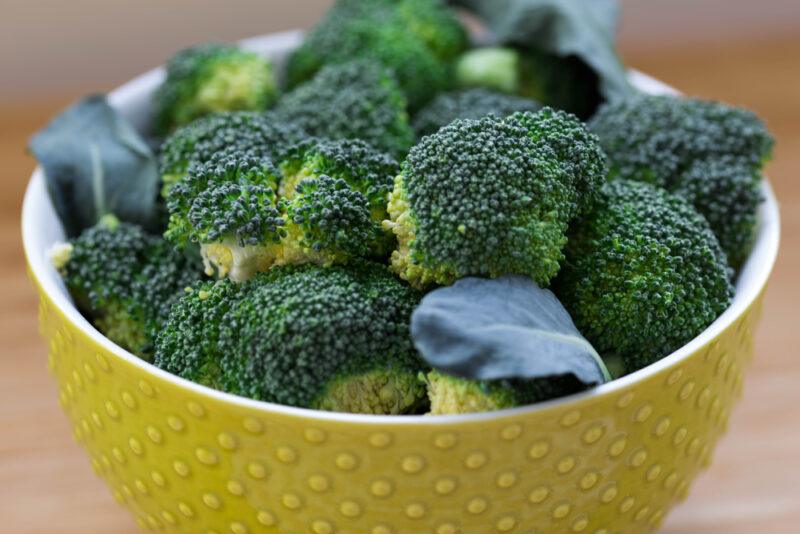 a closeup image of a yellow bowl with white rim full of broccoli florets