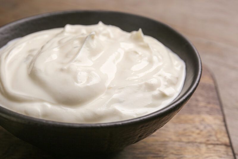 on a wooden surface is a black ceramic bowl full of sour cream