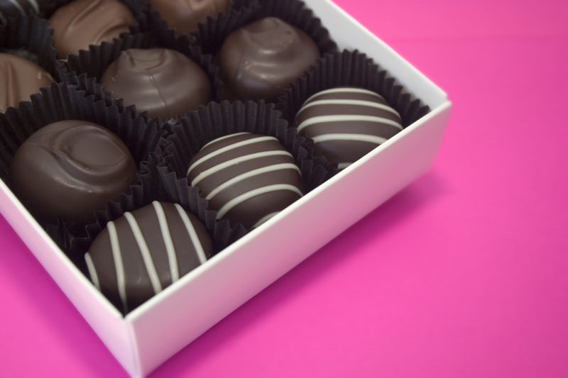 an assortment of chocolate truffles inside a box. 