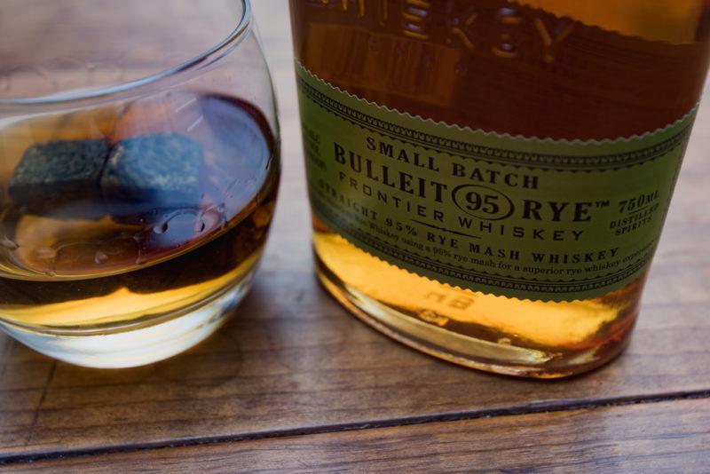 bulleit rye whiskey bottle with glass and whiskey stones