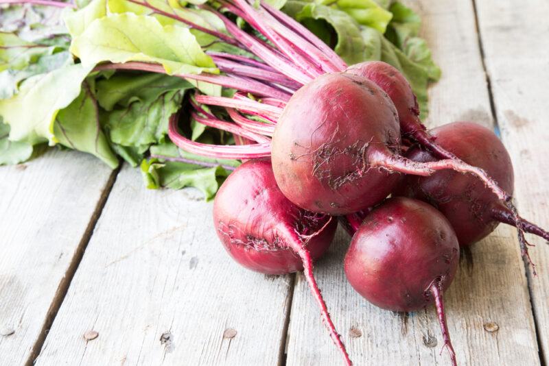 a bunch of fresh beets on a wooden surface