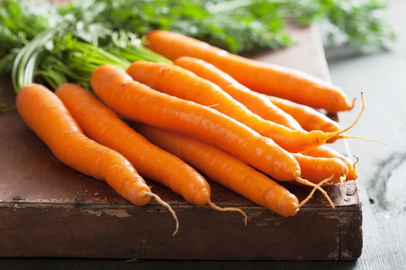 bunch of carrots | Food For Net on a wooden chopping board is a bunch of fresh carrots with leaves still attached