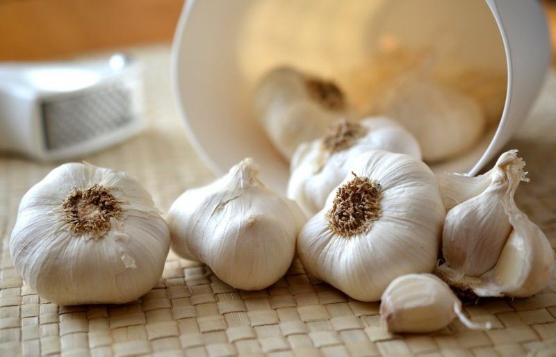 whole garlic spilling out of a white bin onto a table to represent where to buy fresh garlic online 