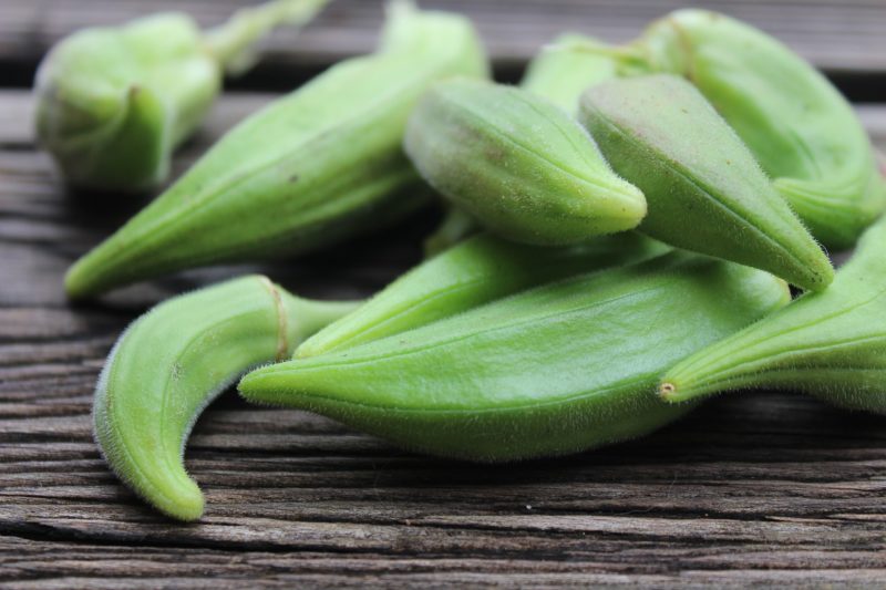 a close up of okra pods on a wooden table to represent where to buy fresh okra online 