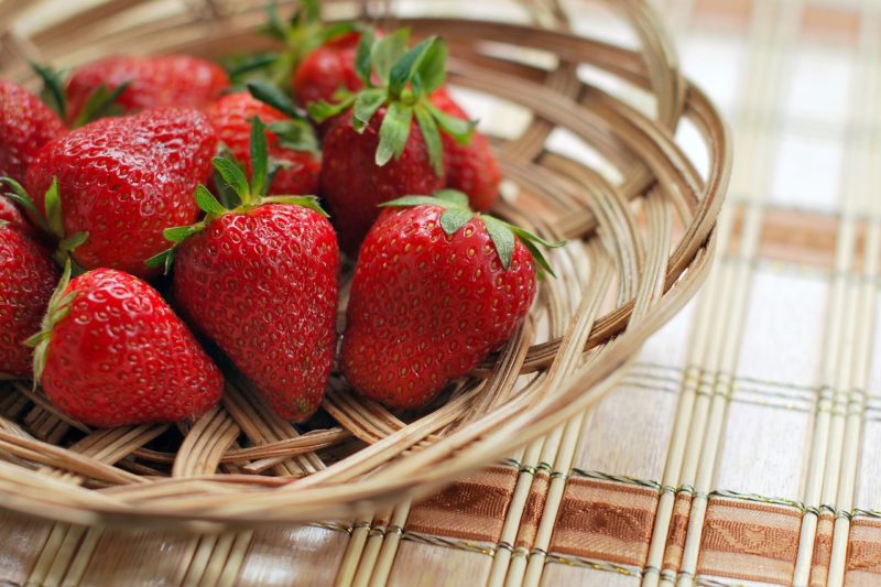 strawberries in a small wooden basket on a table to represent where to buy fresh strawberries online 