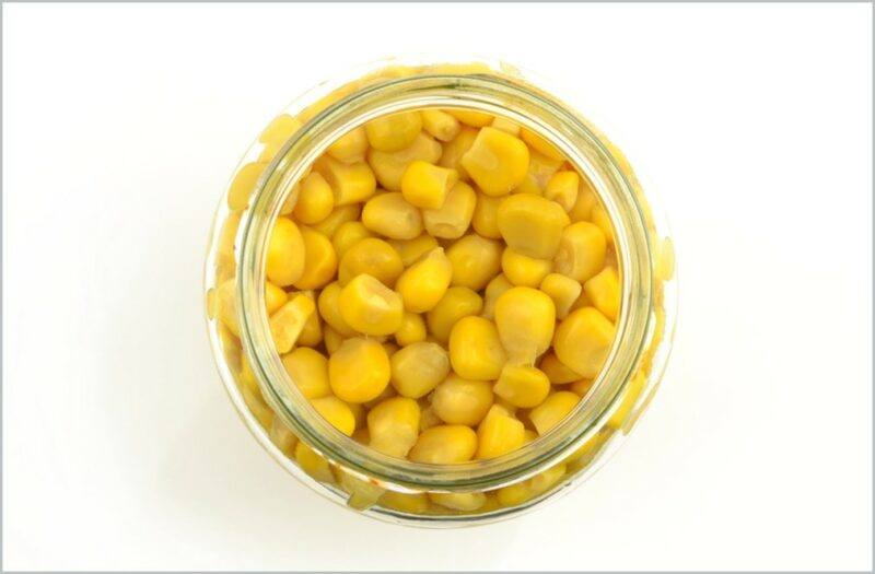 top view image of an open jar of yellow corn kernels