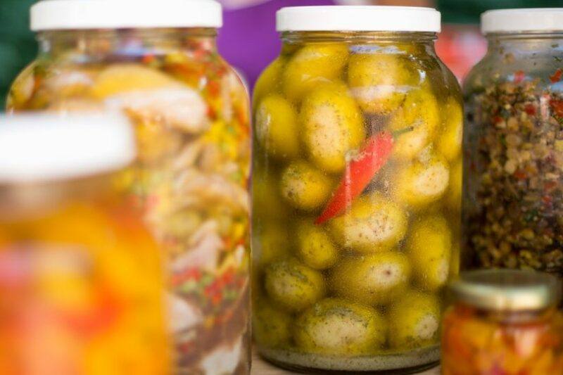 selective focus on a jar full of canned potatoes with a piece of red chili in it