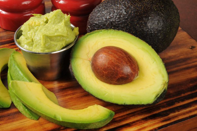 freshly sliced avocado on a. wooden table | Food For Net avocados on a table, some mashed, some whole, some sliced and peeled
