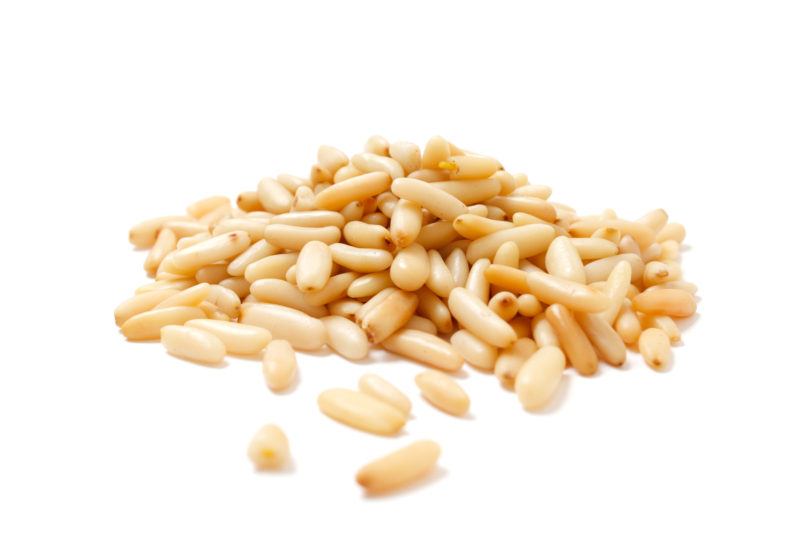 closeup shot of pine nuts on a white background | Food For Net a handful of pine nuts with a white background