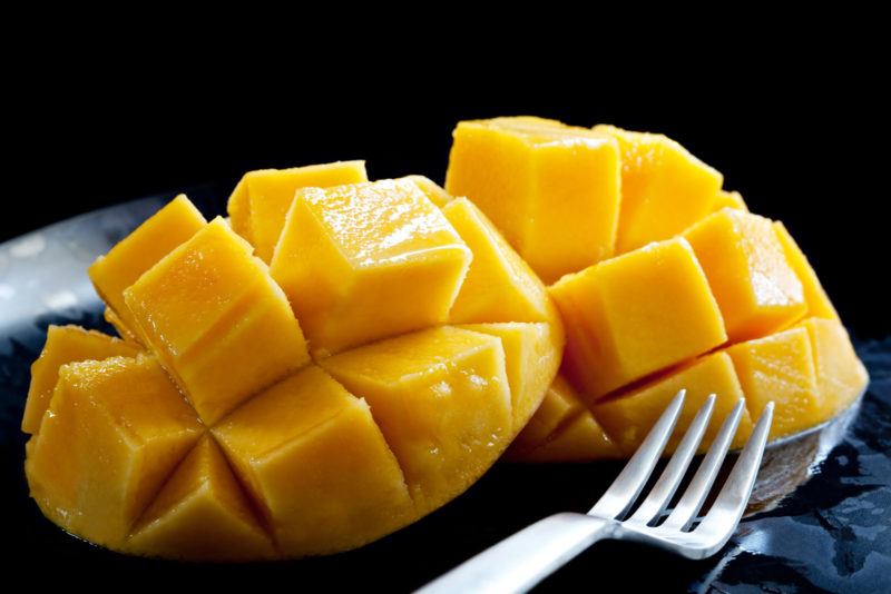 fresh mango cheeks sliced into cubes | Food For Net closeup shot of mago slices in a black background