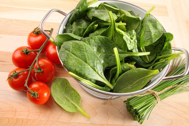 bowl filled with fresh spinach leaves | Food For Net top shot of spinach leaves on a glass bowl