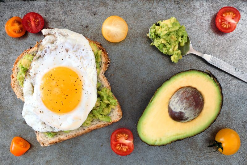 top shot of an open faced sandwich with mashed avocado and fried egg on top