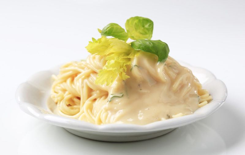 spaghetti with white sauce from heavy cream topped with a sprig of basil