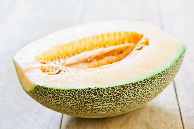 on a wooden surface is a closeup image of a halve cantaloupe