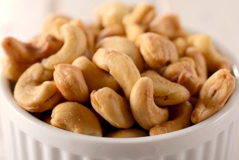 a white textured surface is a white dish with cashews