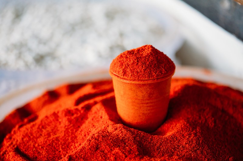 a closeup image of a mound of cayenne powder with a small glass full of cayenne powder on top of it