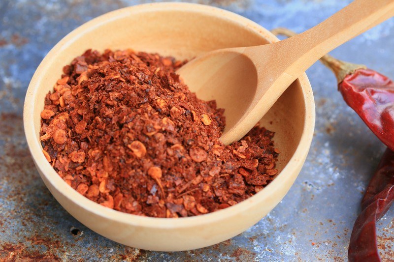 closeup image of a wooden bowl and spoon with cayenne pepper