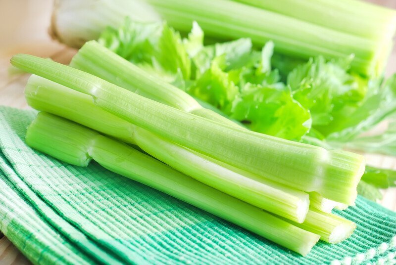 Several stalks of celery rest on a green cloth.