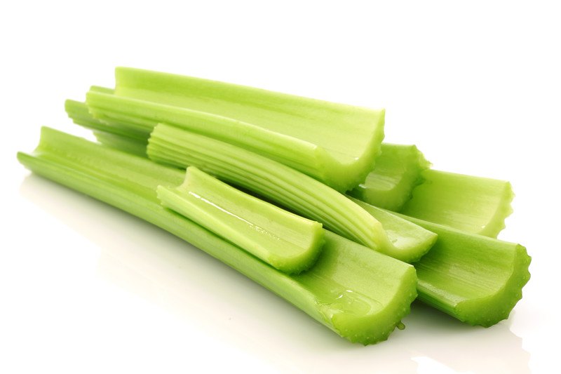 Several green stalks of celery rest against a white background.