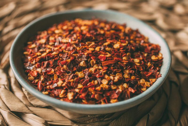 a shallow bowl of chili flakes resting on a weaved place mat