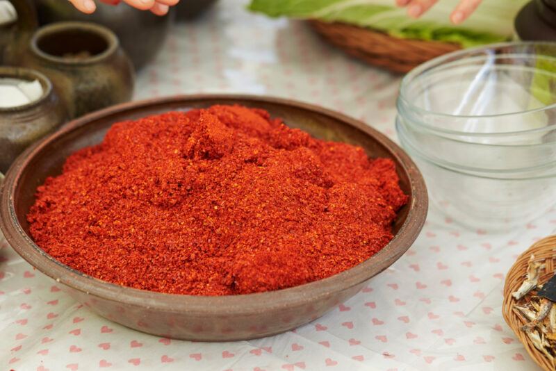 a shallow ceramic brown bowl full of chili powder with various small dishes around it