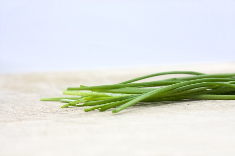 closeup image of a bundle of fresh chives on a wooden surface