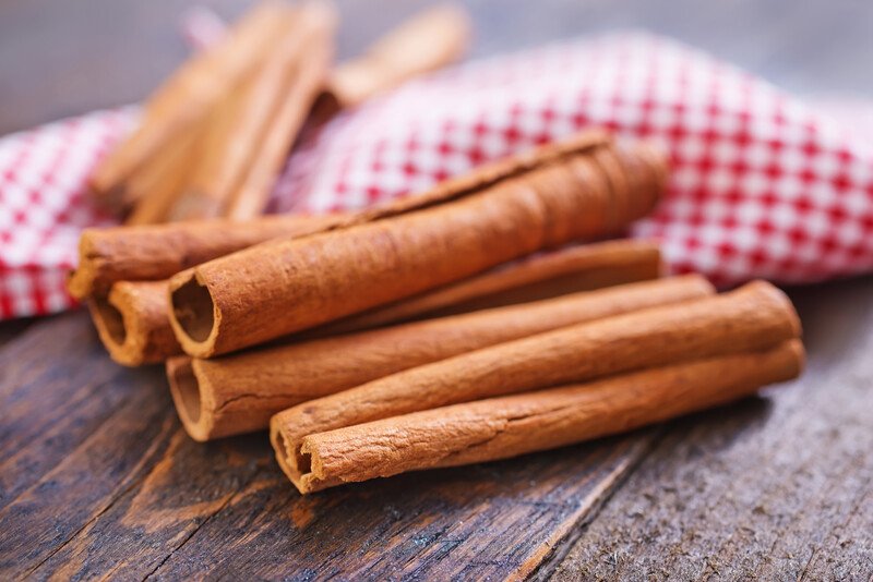 closeup image of cinnamon sticks on a dark wooden surface with red and white kitchen towel