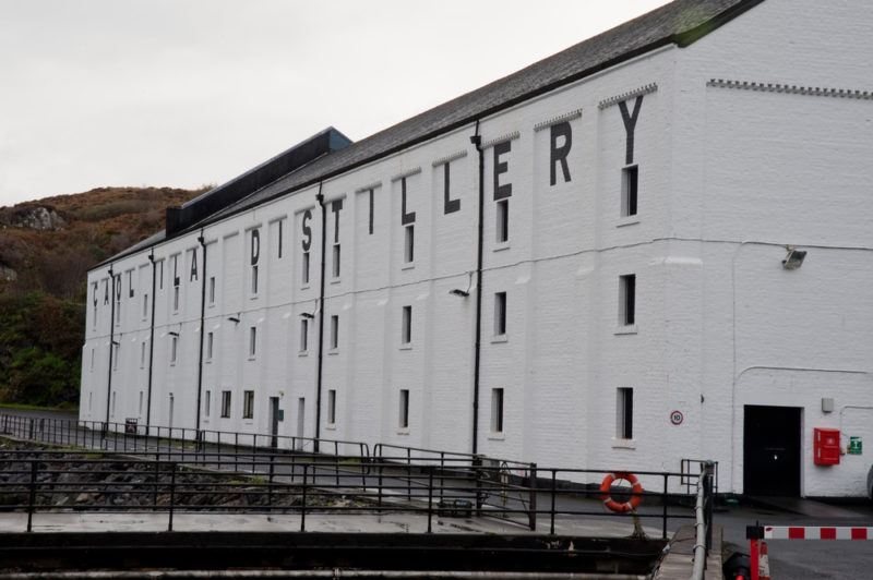 close photo of caol ila distillery with white building and black lettering